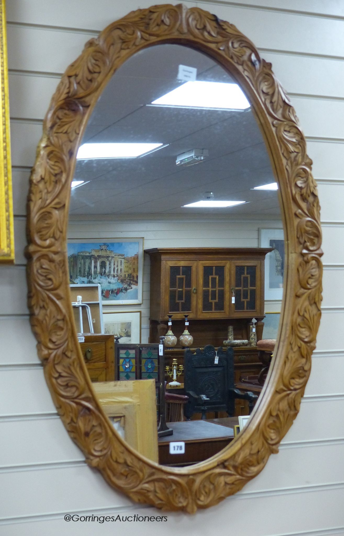 A carved oak oval framed wall mirror, width 70cm, height 109cm